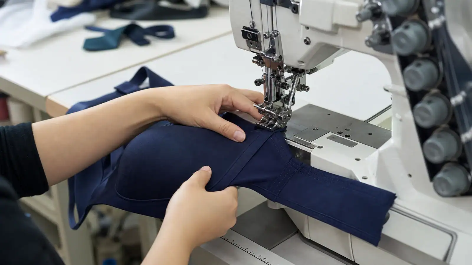 Close view of a sample machinist sewing elastic and cup seams on a sports bra prototype