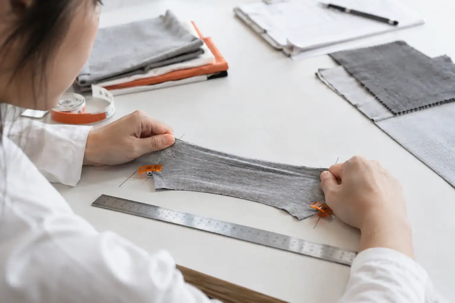 Person measuring fabric swatch for custom clothing production.