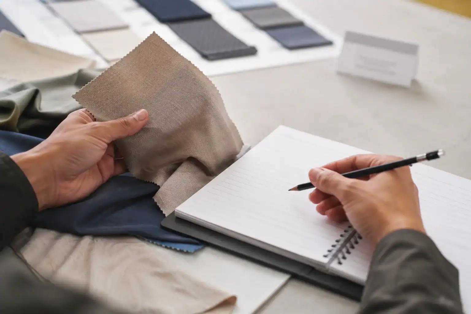 Persona revisando muestras de tela y dibujando diseños de ropa en un estudio de diseño.