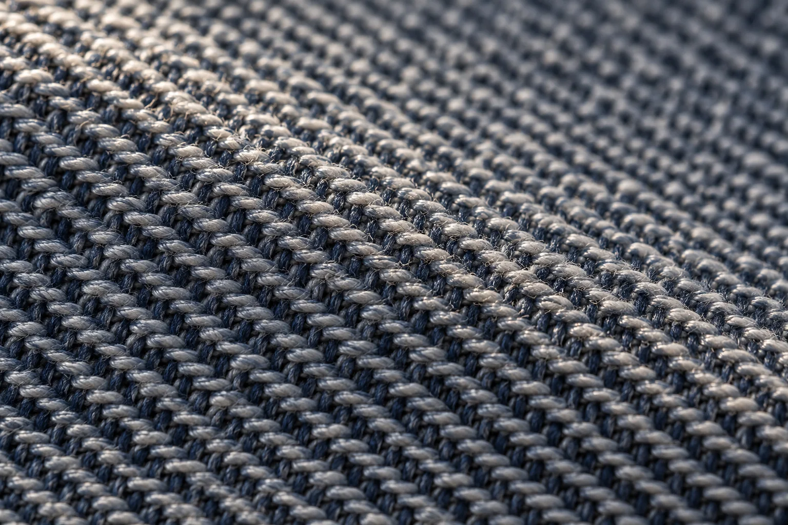 Macro textile study showing a clear diagonal twill line, warp and weft crossings, and a subtle raised rib, no text