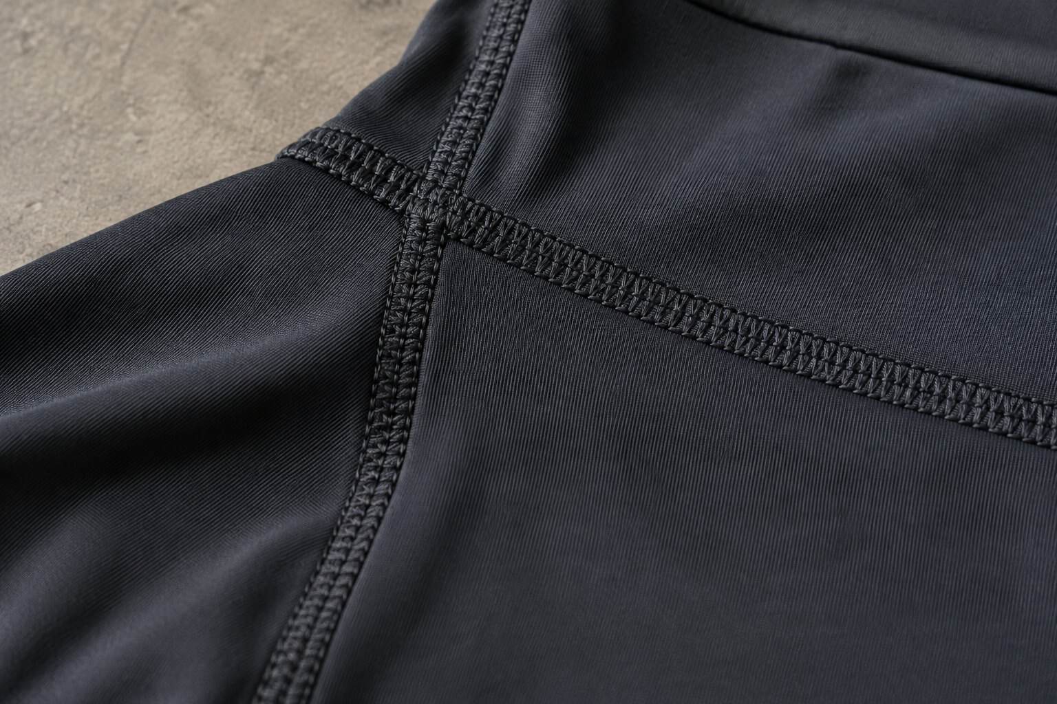 Close-up of black activewear fabric with flatlock stitching.
